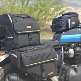 Touring motorcycle loaded with multiple black pannier bags, a top case, and a tail bag on a blue Royal Enfield.