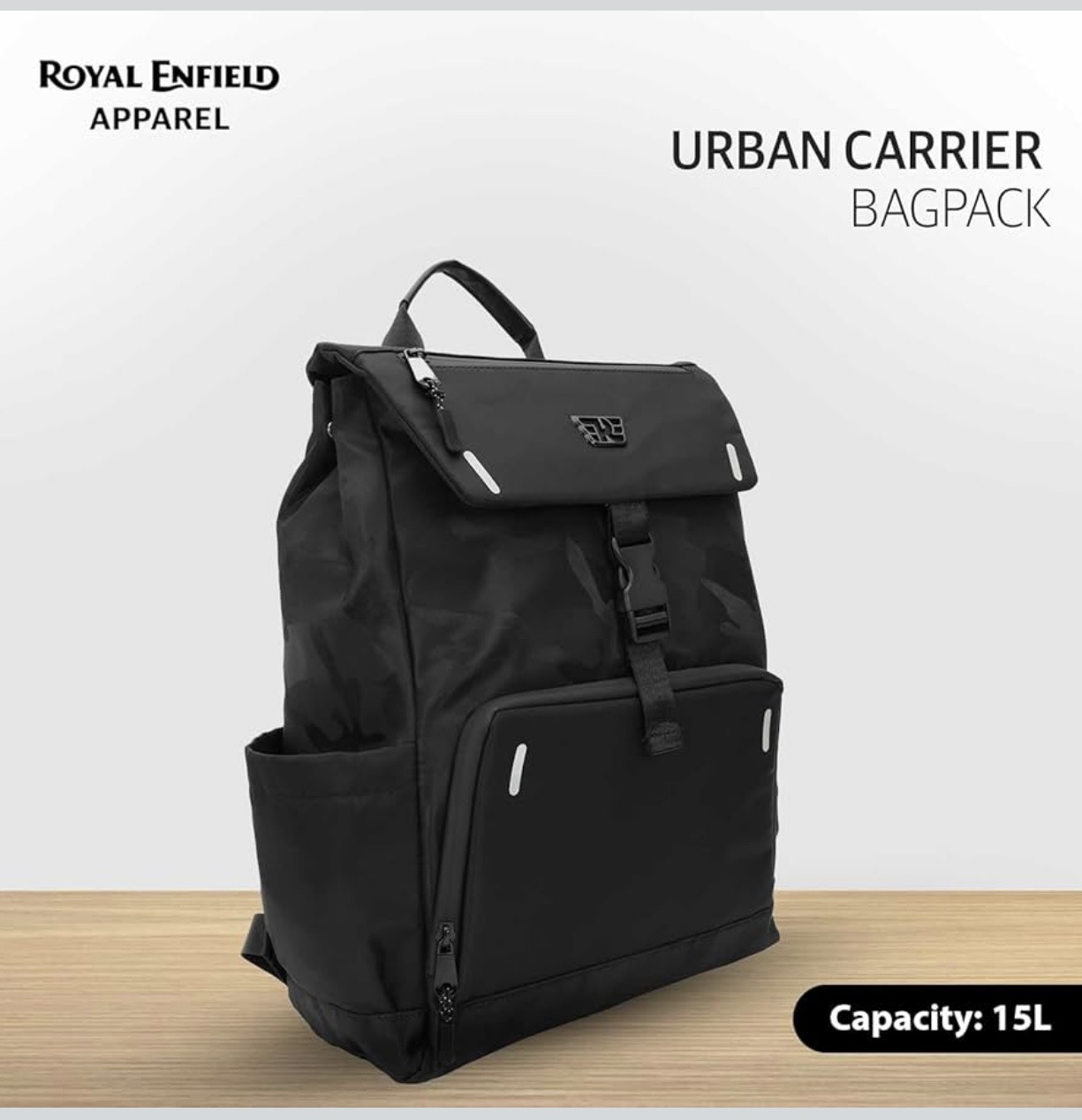 Screenshot - laxmiautocare.com Black Urban Carrier backpack with top flap, buckle strap, and front and side pockets; 15L capacity (Royal Enfield Apparel).