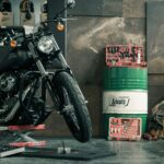 Black motorcycle on a lift in a cluttered workshop with helmets and boxes in the background