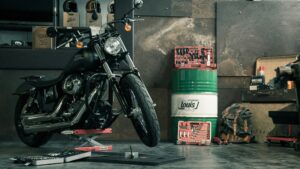 Black motorcycle on a lift in a cluttered workshop with helmets and boxes in the background