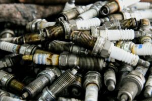 Pile of used spark plugs piled together, rusty and dirty automotive parts