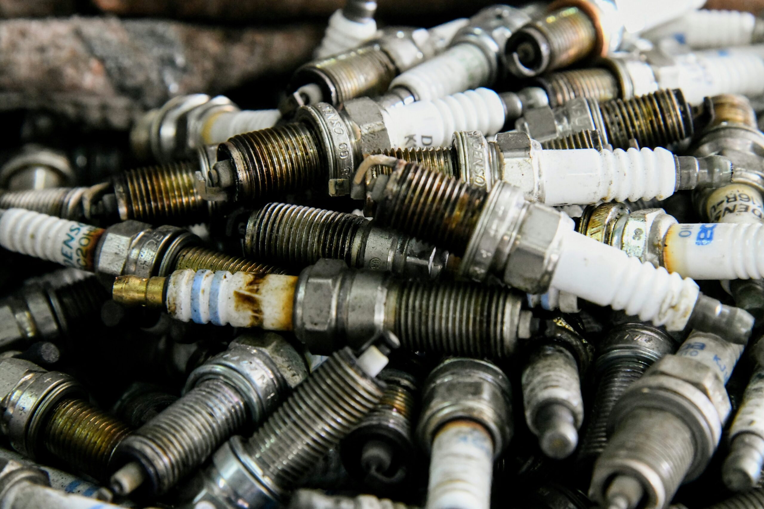 Pile of used spark plugs piled together, rusty and dirty automotive parts