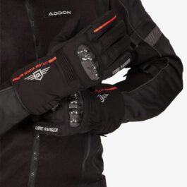 Screenshot - laxmiautocare.com Person wearing a black motorcycle jacket and protective winter gloves with red accents and brand logos (Addon, Lone Ranger).